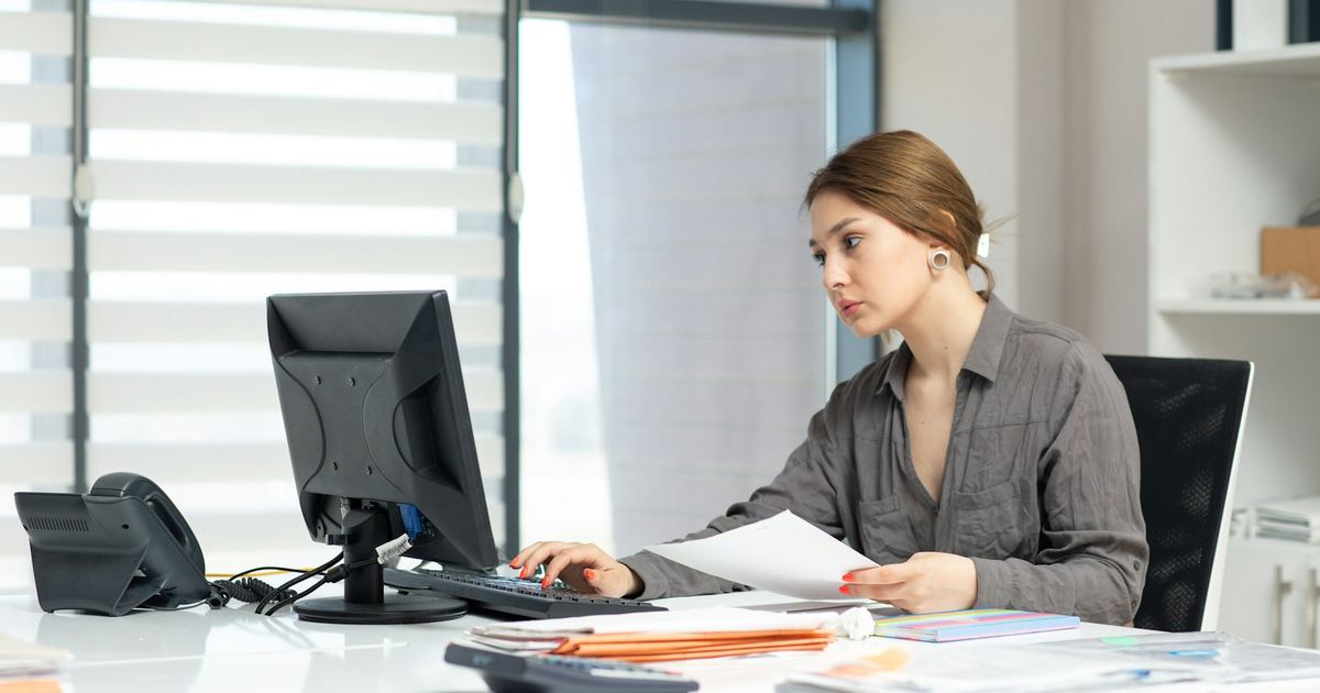 Une comptable vérifiant une pièce à son poste de travail